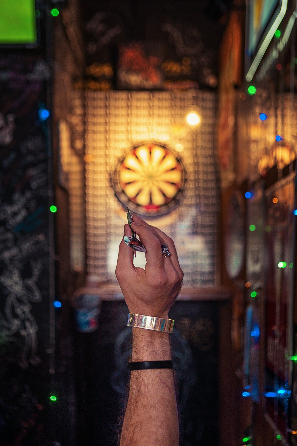 Person wirft einen Dart in einer stylischen Bar mit Neonlicht